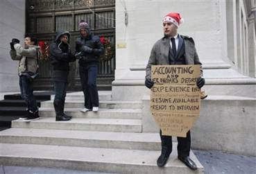 In this Dec. 15, 2010 photo, Jesse Paloger holds up a sign while standing on Wall Street as he hopes to find a job, in New York. Paloger, who has an accounting and economics degree from the University of California, Santa Barbara, has written on the bottom of his sign, 'Go-getter from California looking for my shot!' Fewer people applied for unemployment benefits last week, the third drop in the past four weeks and a sign that the job market is slowly improving.